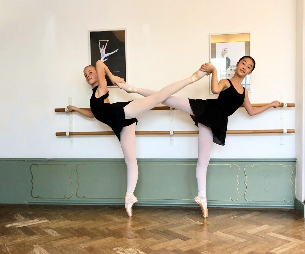 two ballet girls in arabesque on pointes